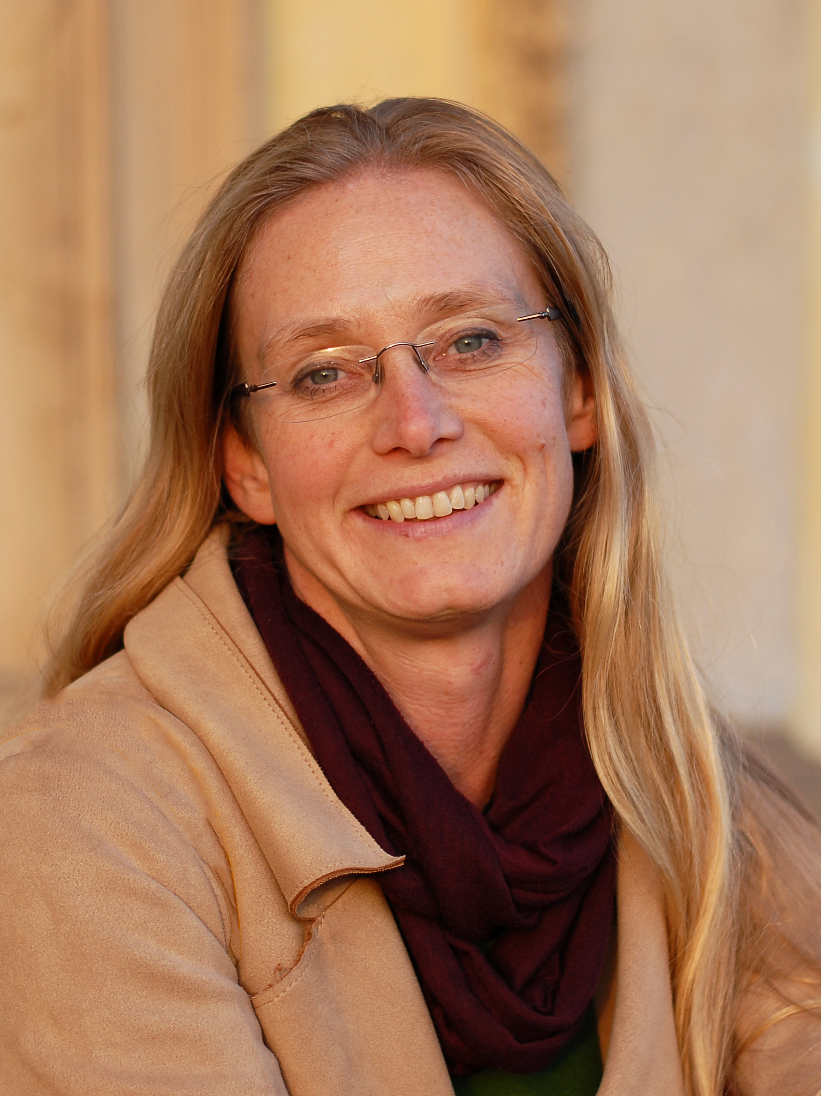 Startseite Therese Berg, Trauma-Coach und Begleiterin für heilsames Schreiben, lächelt mit Brille und weinrotem Schal freundlich in die Kamera.